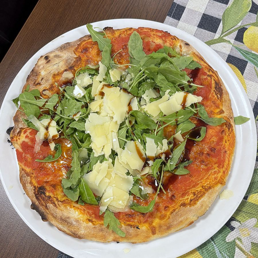 Pizza mit Rucola, gehobeltem Parmesan und Balsamico